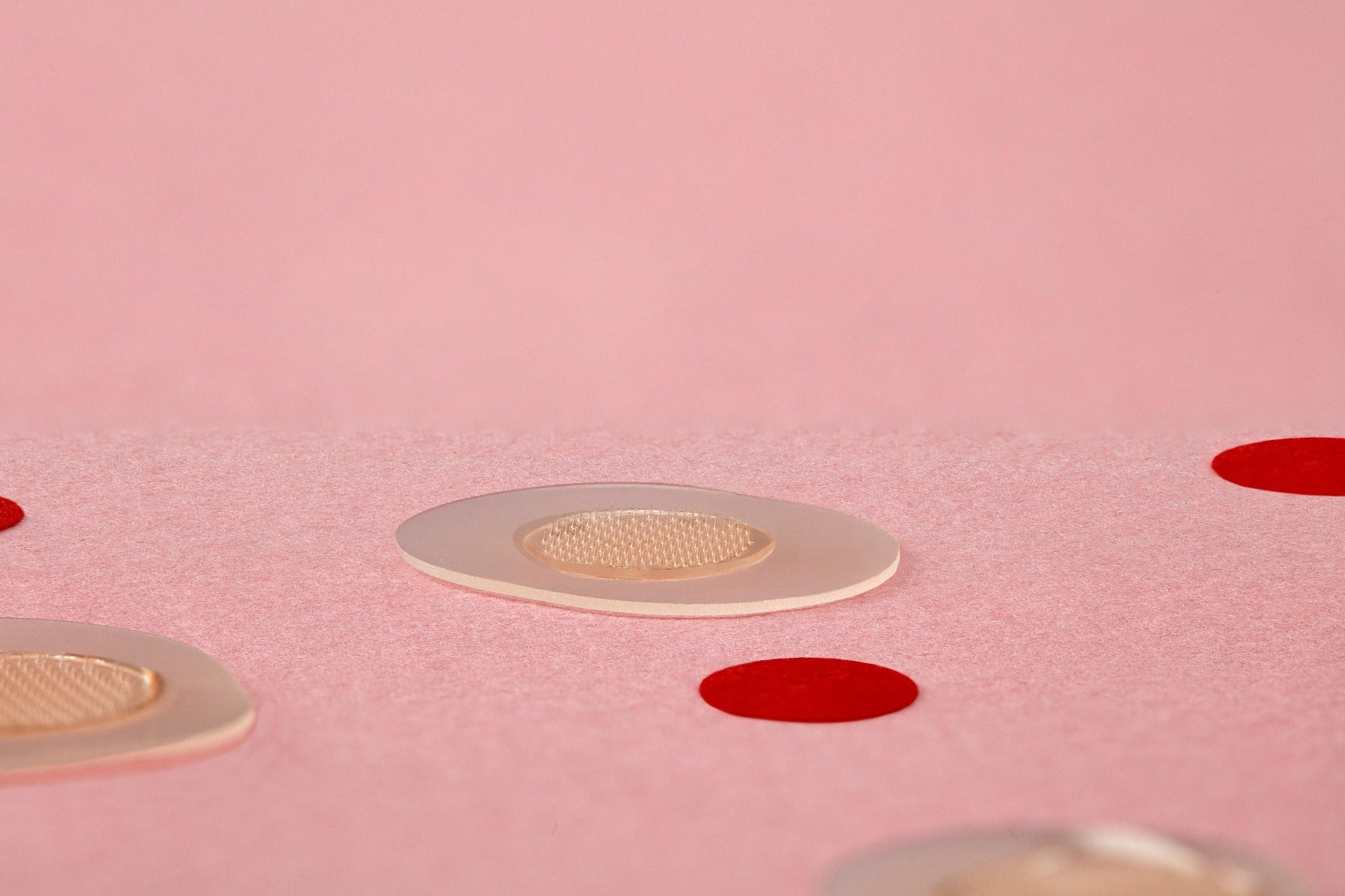 Transparent microneedling patches placed on a pink textured background for acne spot treatment.