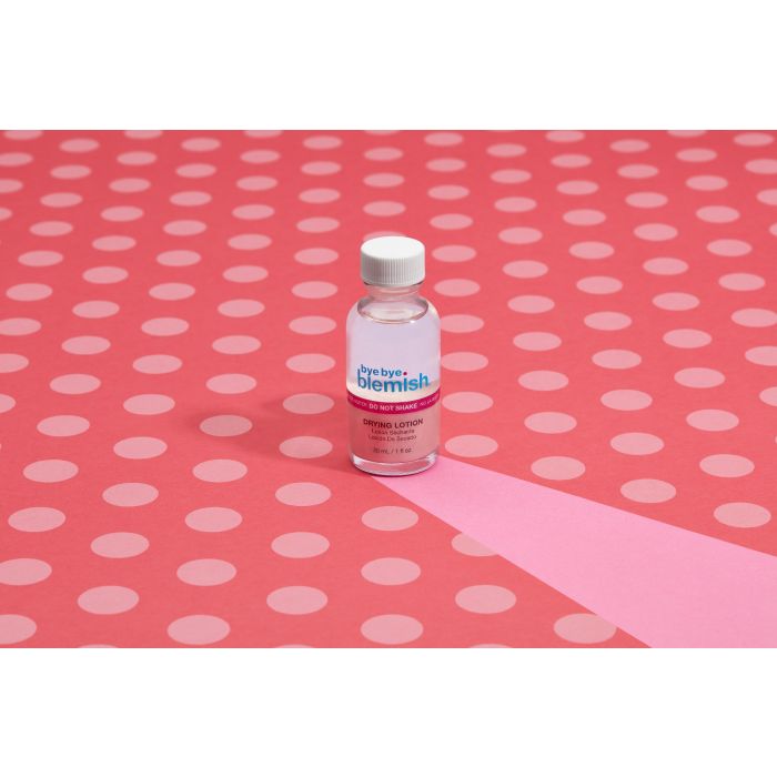 Bye Bye Blemish Drying Lotion on Pink Dots – Acne treatment bottle displayed on a pink polka dot background for skincare aesthetics.